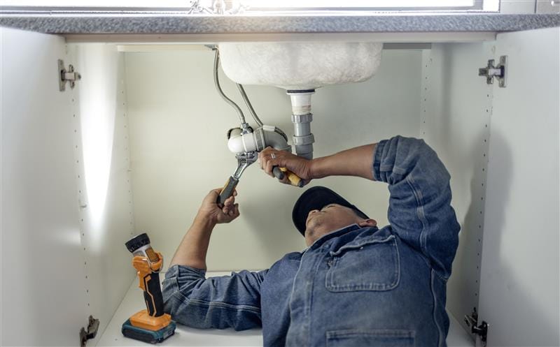 Plumber repairing pipes beneath a bathroom sink in Dublin
